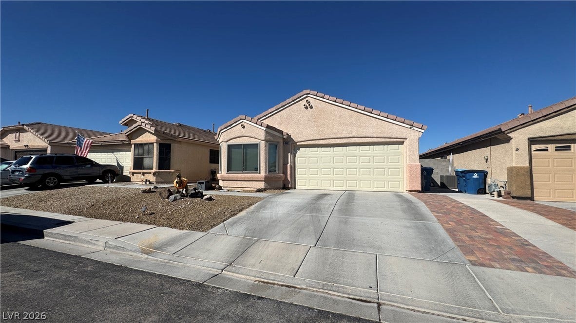 Clean lines and a spacious driveway define this desert-style home facade under clear blue skies.