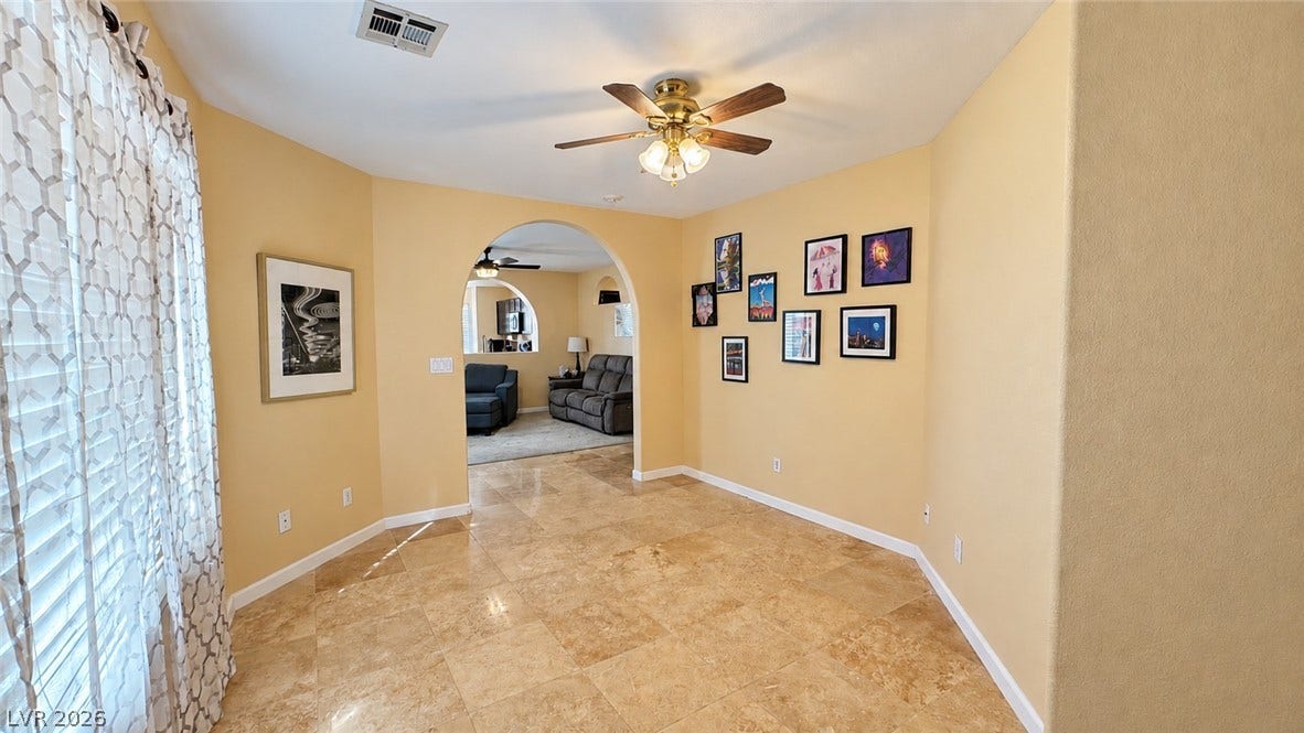 Polished tile flooring sweeps through a versatile dining space highlighted by an arched doorway.