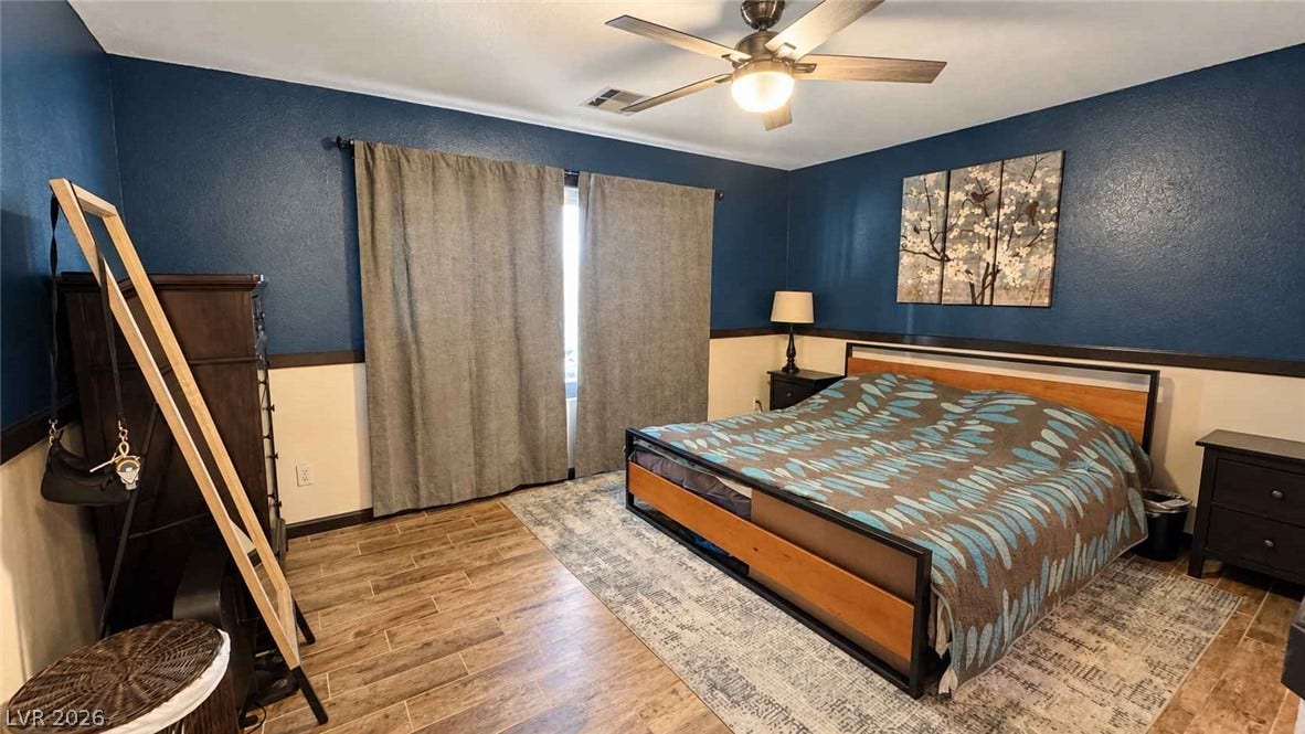 Rich wood plank flooring accents this comfortable bedroom retreat.