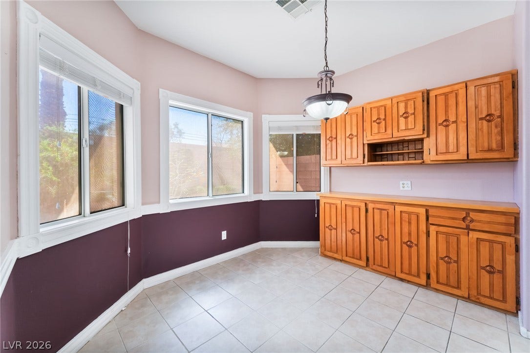 Tiled flooring and wood cabinetry define this versatile breakfast area surrounded by windows.