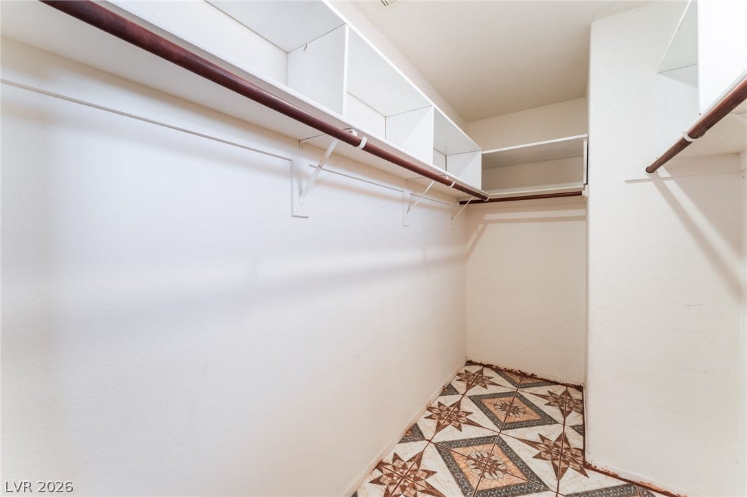 Ample built-in shelving and hanging rods maximize storage space above detailed tile flooring.