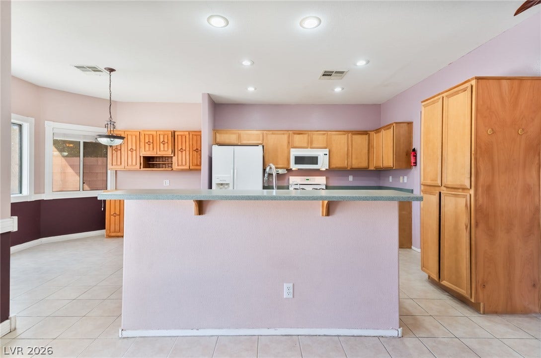 Tiled flooring and wood cabinetry define this functional culinary space designed with a central peninsula.