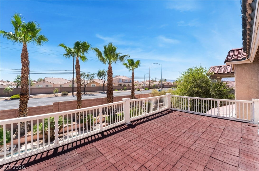 A spacious upper-level balcony features durable tile flooring and views of mature palm trees.