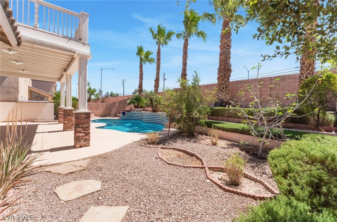 A private swimming pool highlights this backyard oasis framed by towering palm trees.