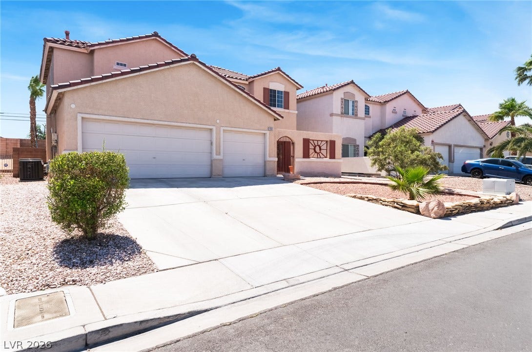 Spanish tile roofing and a spacious concrete driveway define this multi-level stucco residence.