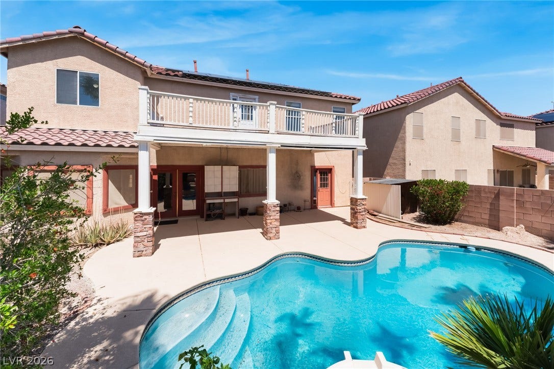 An inviting backyard oasis features a shimmering in-ground pool and a covered patio structure.