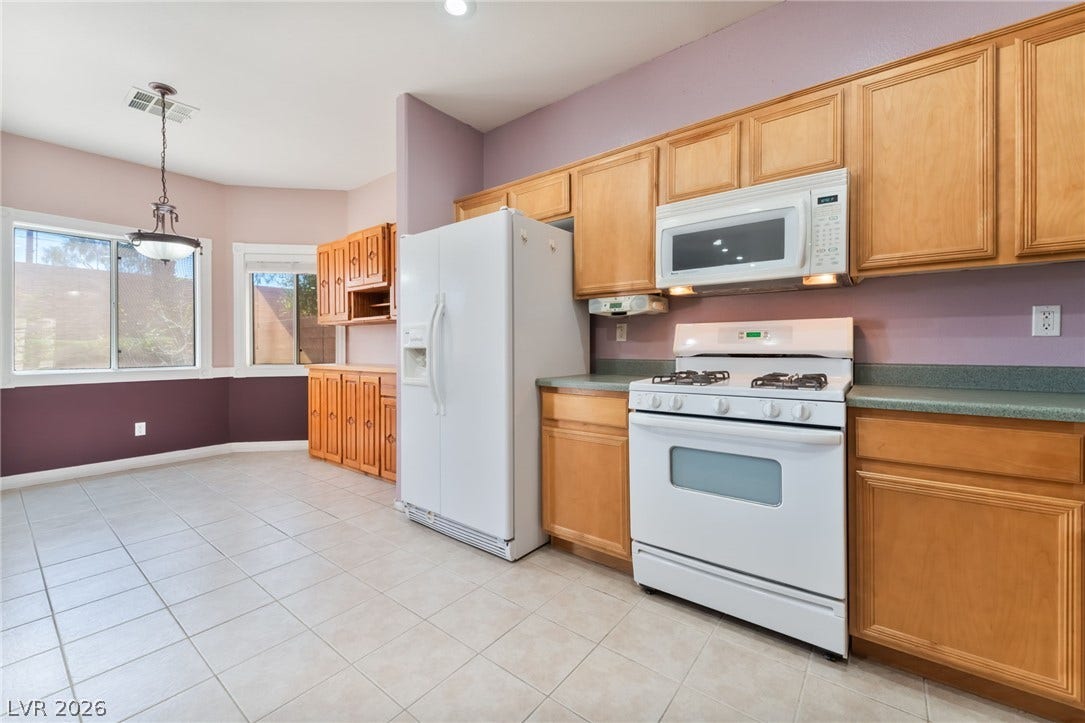 Ample wooden cabinetry and tile flooring define this functional cooking and dining space.