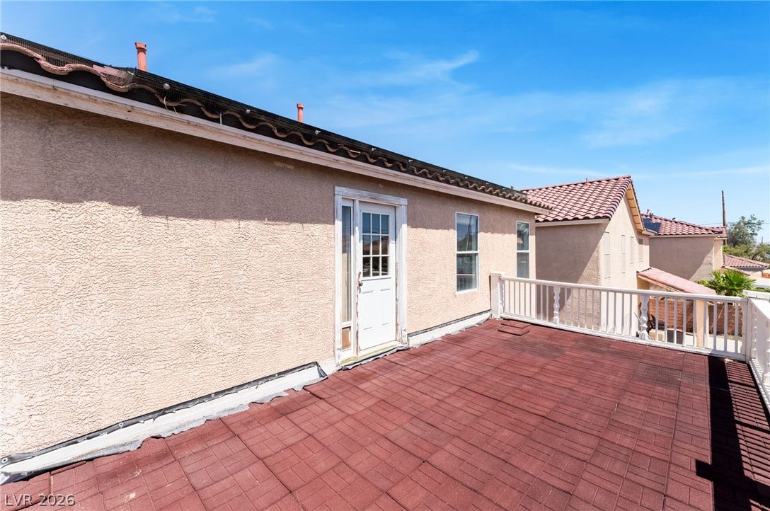 A spacious rooftop terrace features durable tiled flooring and classic white railing under clear skies.