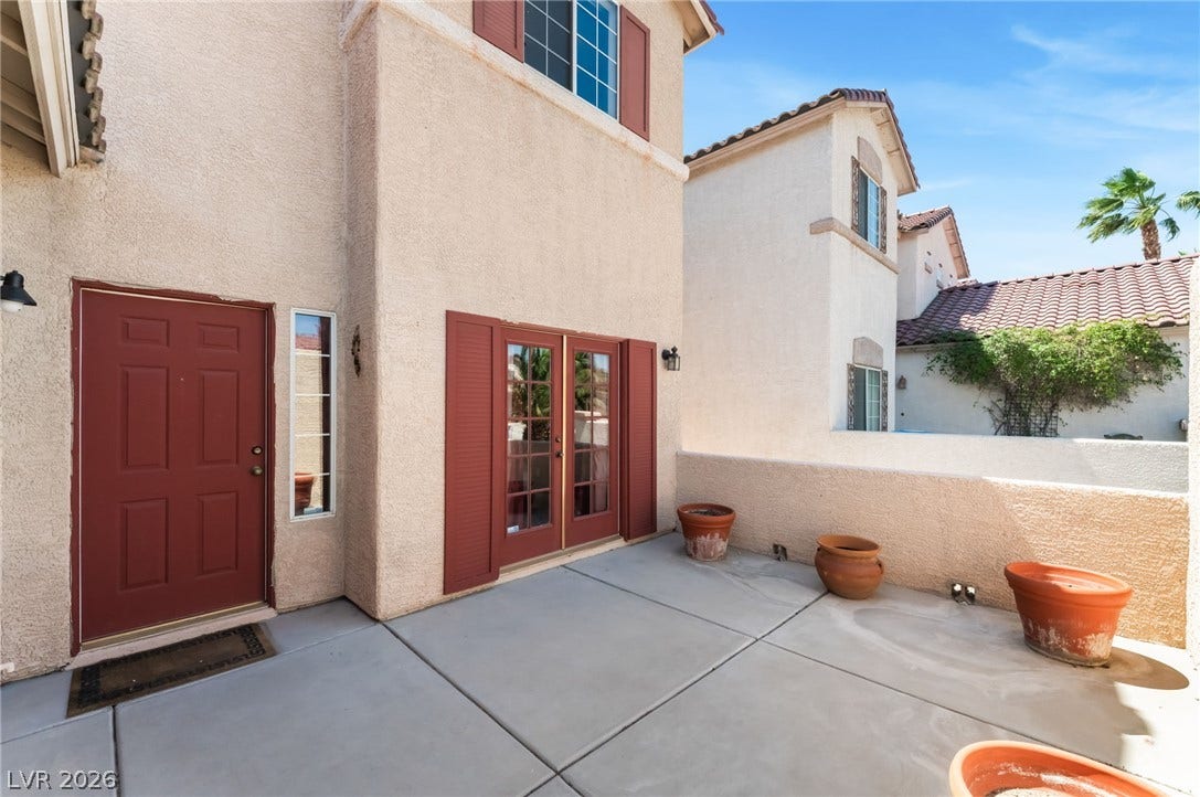 Concrete patio tiles create a clean outdoor living space adjacent to the stucco exterior.