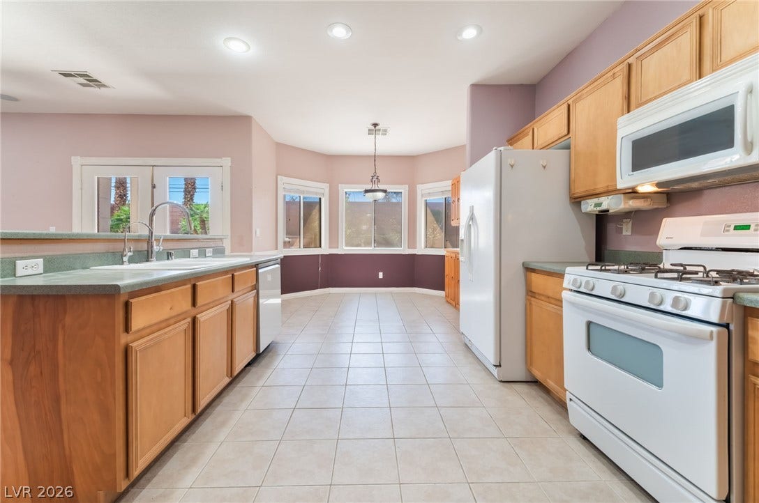 Ample wooden cabinetry and ceramic tile flooring define this highly functional kitchen layout.
