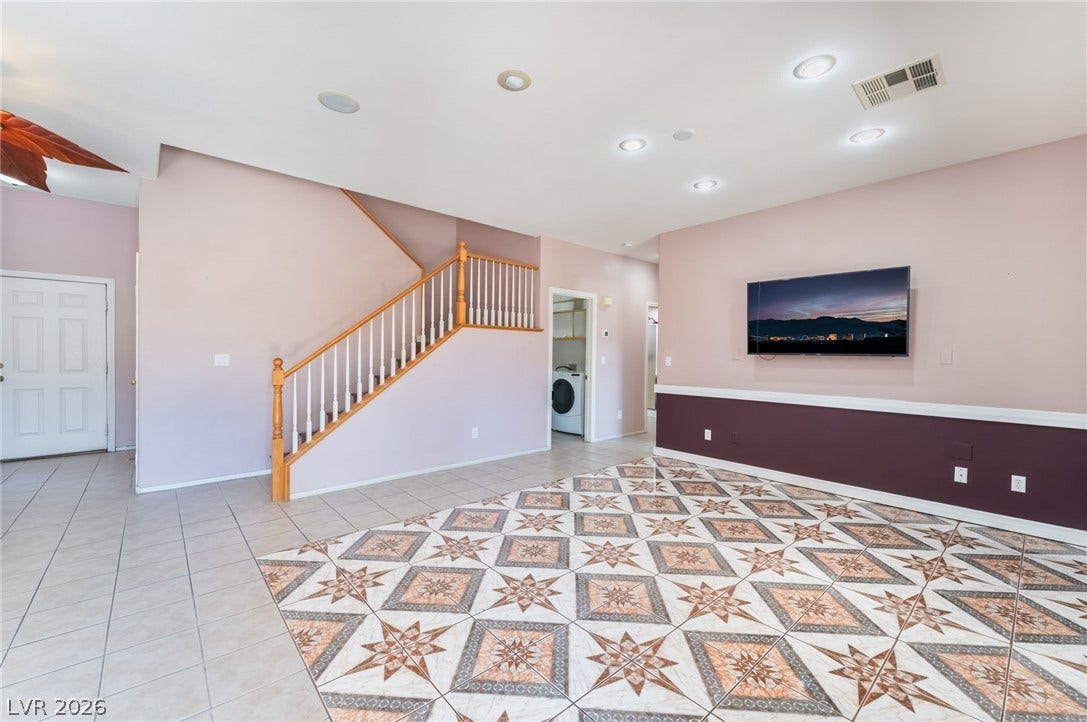 Ornate tiled floors and a classic staircase define this spacious living area.