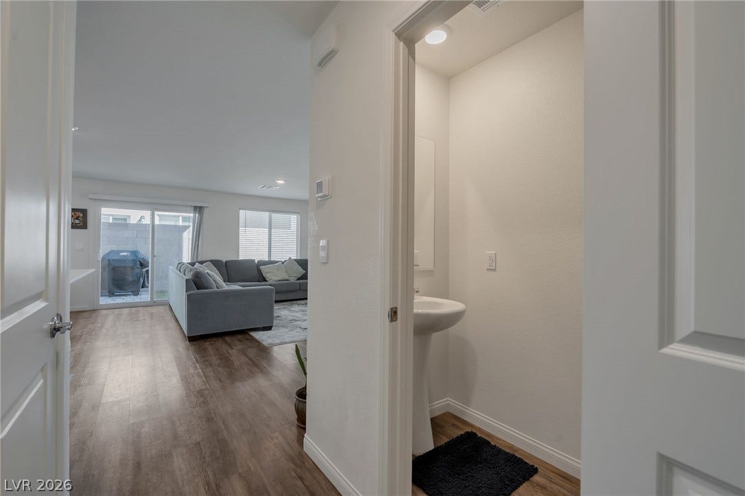 3428 Rush Avenue, Las Vegas, NV 89141 Gleaming wood-look floors flow seamlessly from a convenient powder room into the open-concept living space.