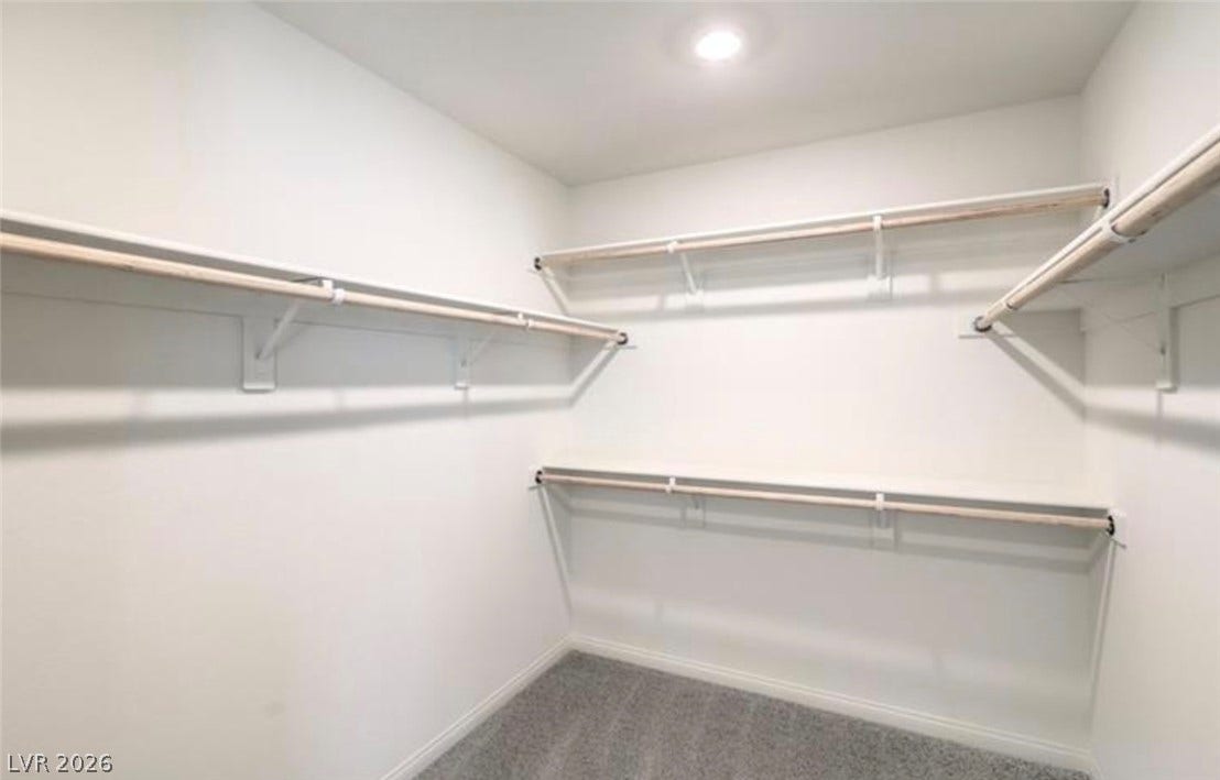 3428 Rush Avenue, Las Vegas, NV 89141 A spacious Primary bedroom walk-in closet features carpeted flooring and built-in shelving with hanging rods.