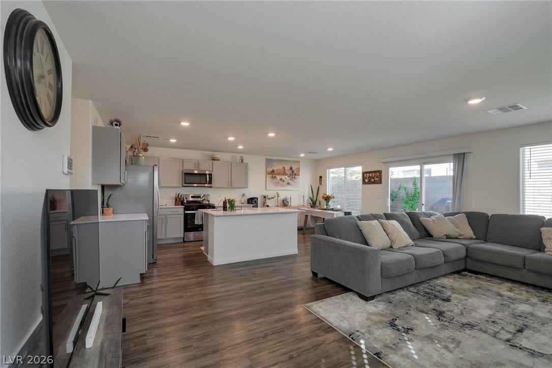 3428 Rush Avenue, Las Vegas, NV 89141 Rich wood-look flooring anchors a seamless transition from the living room to the kitchen.