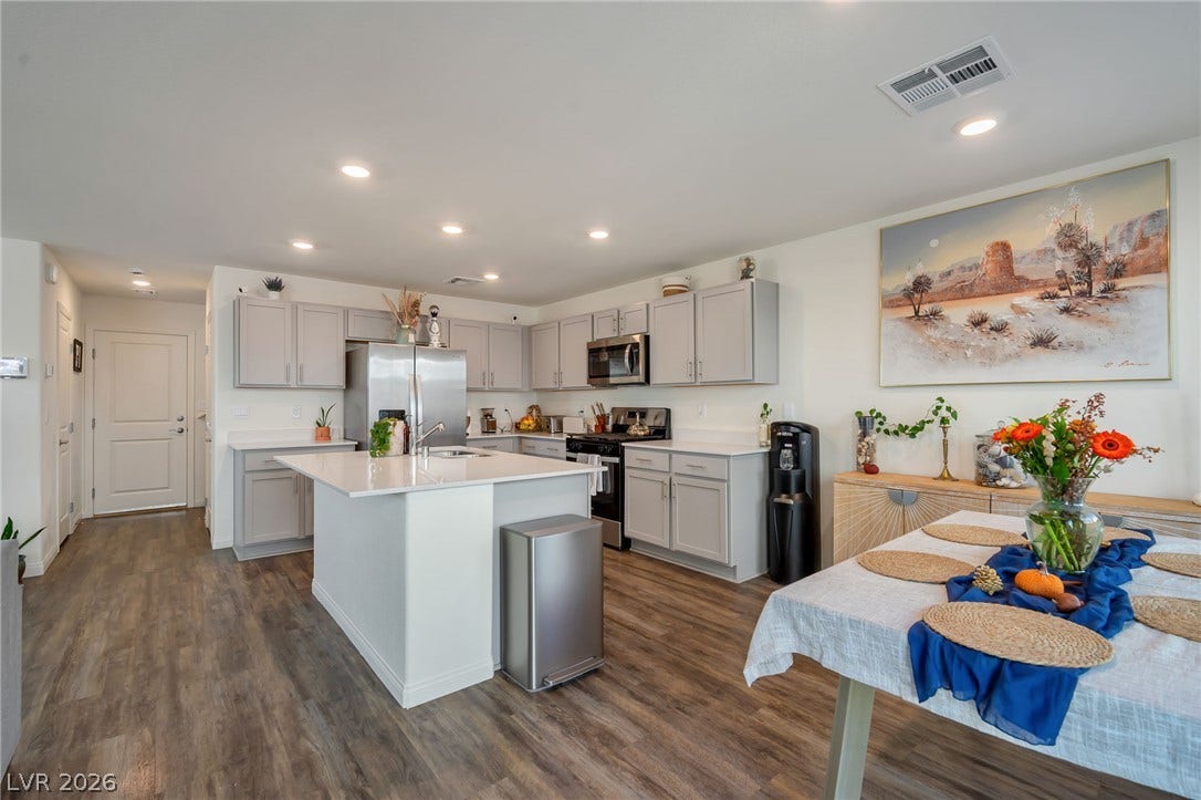 3428 Rush Avenue, Las Vegas, NV 89141 An open kitchen features modern cabinets, a central island, and wood-patterned flooring throughout.