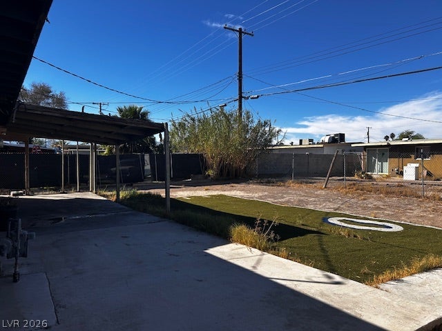 3708 Perliter Avenue, North Las Vegas, NV 89030 An expansive fenced backyard features a covered concrete patio under clear desert skies.