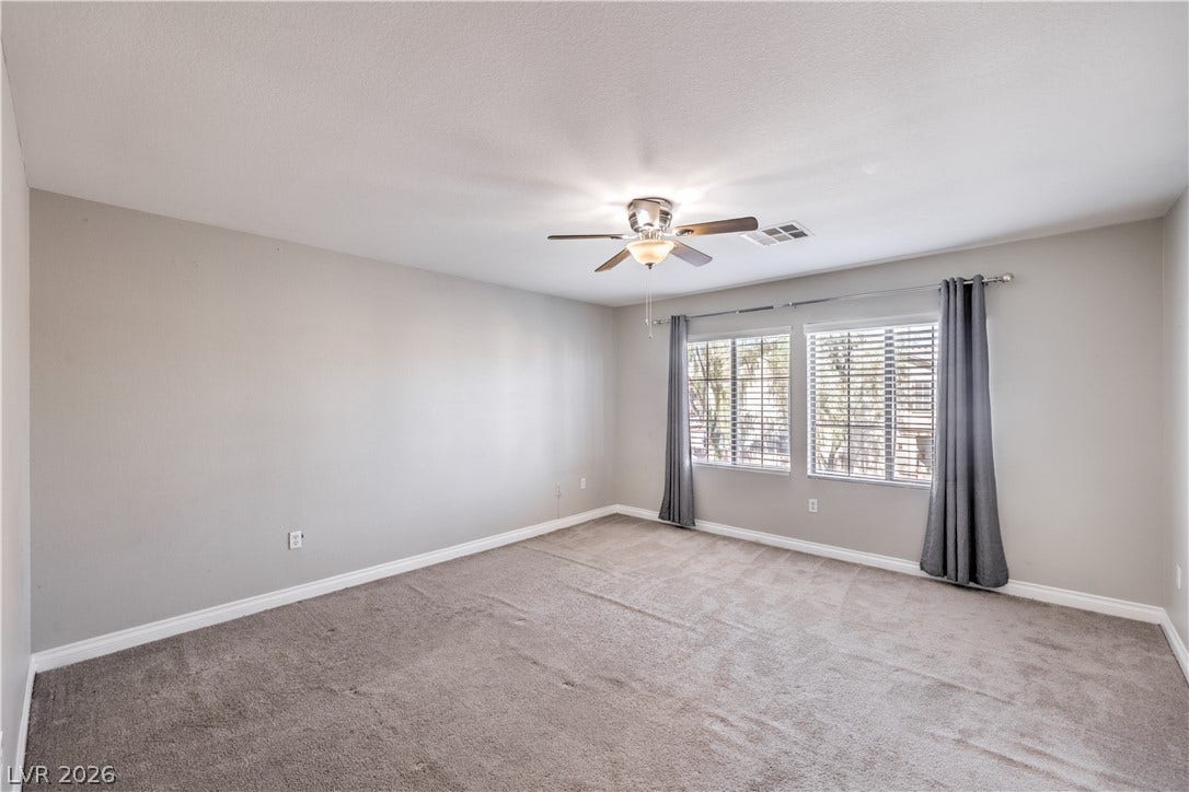 Soft carpeting pairs with neutral walls in this comfortable bedroom space.