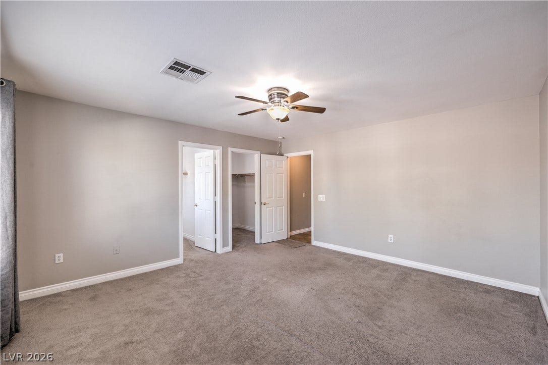 Plush carpeting and baseboard molding frame this serene, comfortable sleeping space.