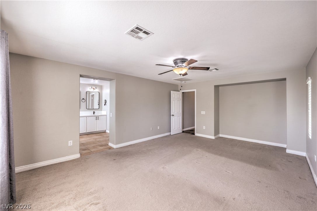 Plush carpeting anchors this spacious bedroom featuring an attached private bathroom suite.