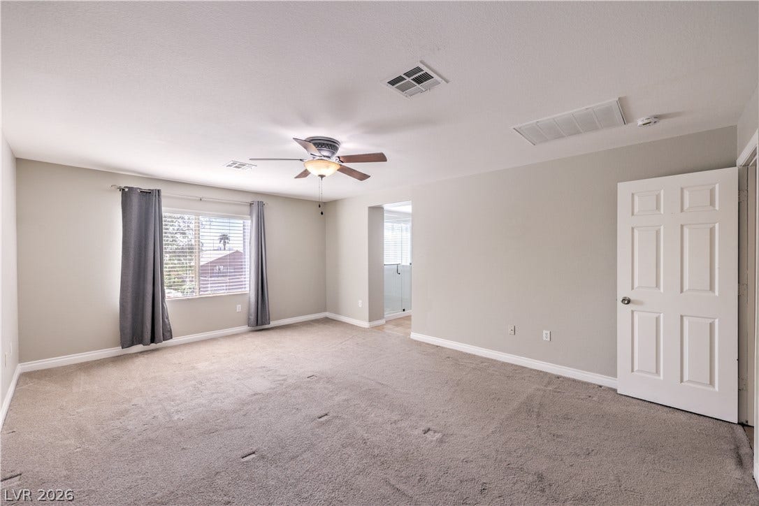 Generous window openings fill this carpeted bedroom space with natural light.