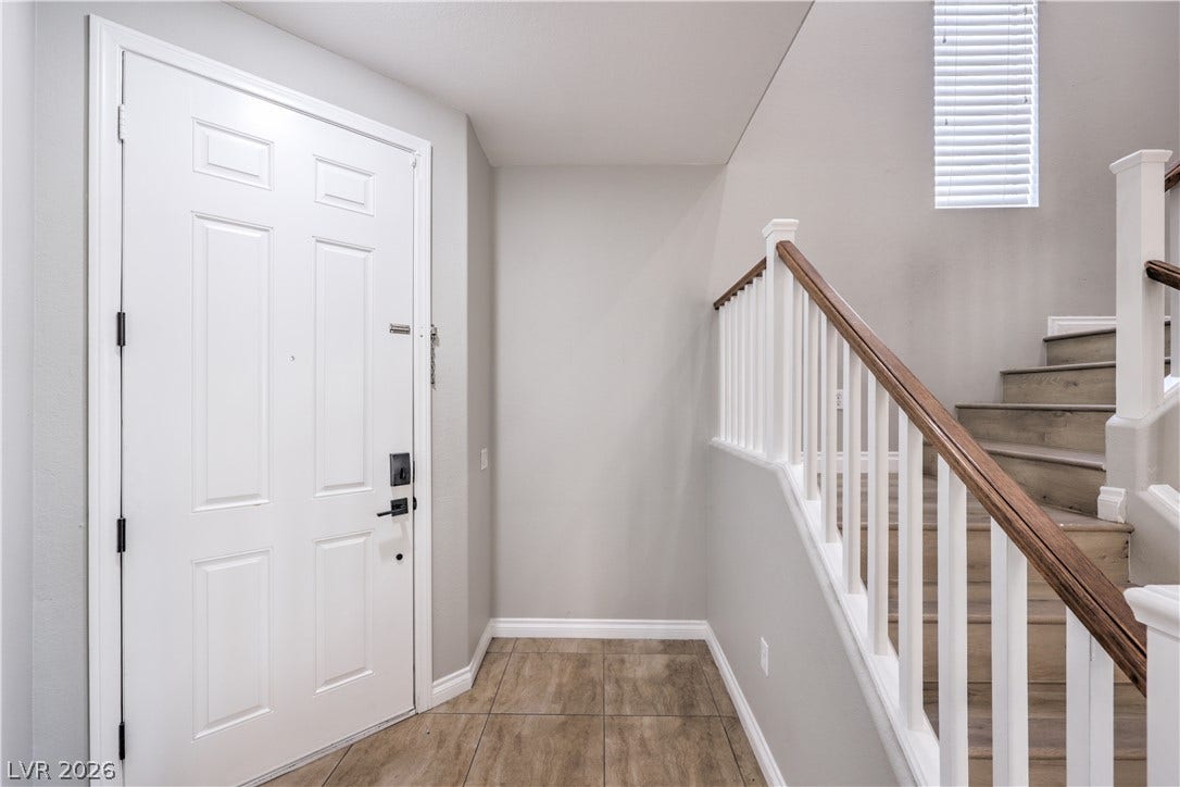 Tiled flooring greets guests at the entryway alongside wood-tread stairs.