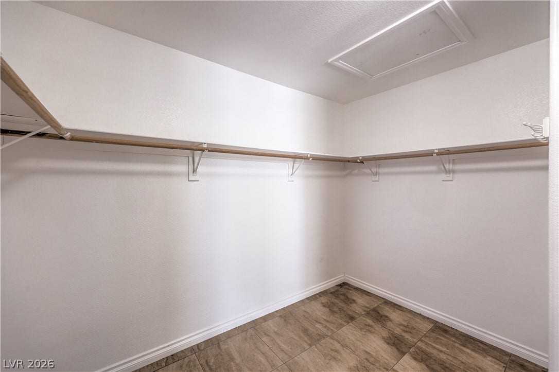 Ample hanging rods and shelving optimize this functional walk-in closet space with tiled flooring.