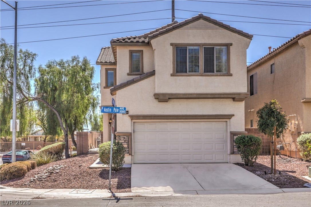 Two-story architecture pairs stucco surfaces with a concrete driveway leading to a two-car garage.