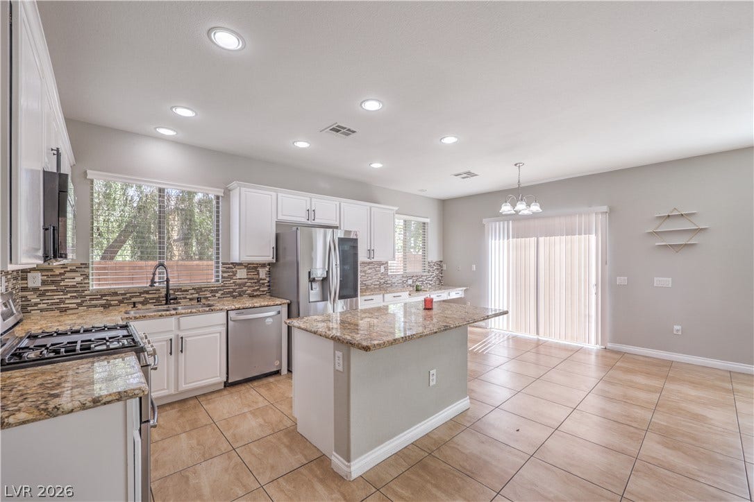 Granite countertops and an island complete this functional kitchen workspace with sliding door access.