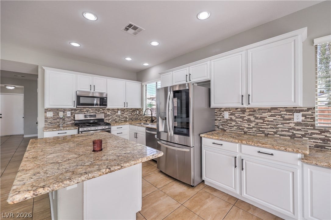 Gleaming stone countertops and matching tiled floors define this spacious, modern workspace.