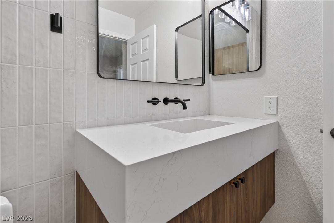 1740 Bluffs Drive, Henderson, NV 89014 Modern vanity features a quartz countertop paired with sleek wall-mounted plumbing fixtures and vertical tile.