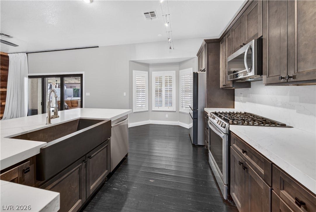 1740 Bluffs Drive, Henderson, NV 89014 Rich dark wood cabinetry and deep-toned floors ground this open kitchen space.