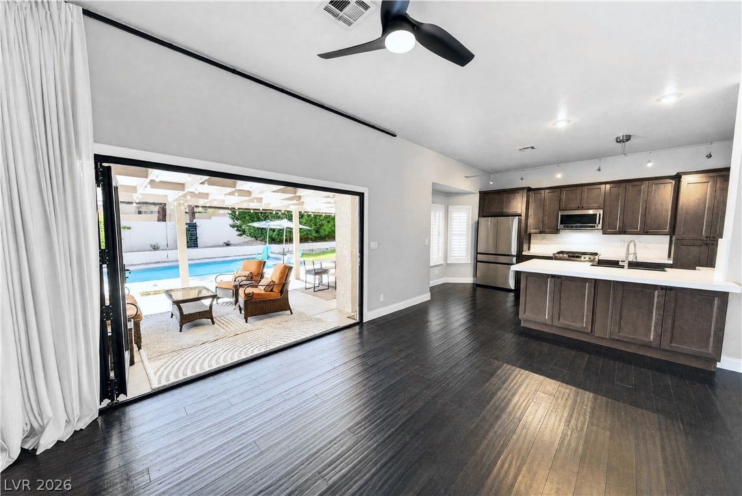 1740 Bluffs Drive, Henderson, NV 89014 Dark wood flooring and wide glass doors connect the interior spaces with the patio and pool.