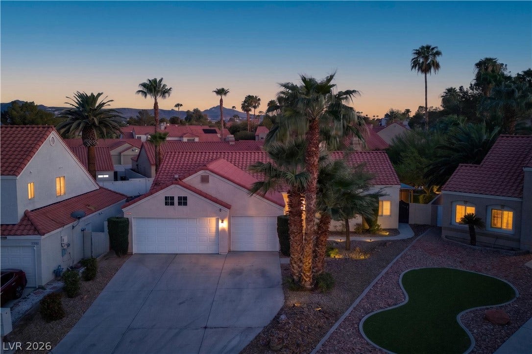 1740 Bluffs Drive, Henderson, NV 89014 Warm dusk lighting illuminates a classic tile roof and palm trees against a twilight sky.