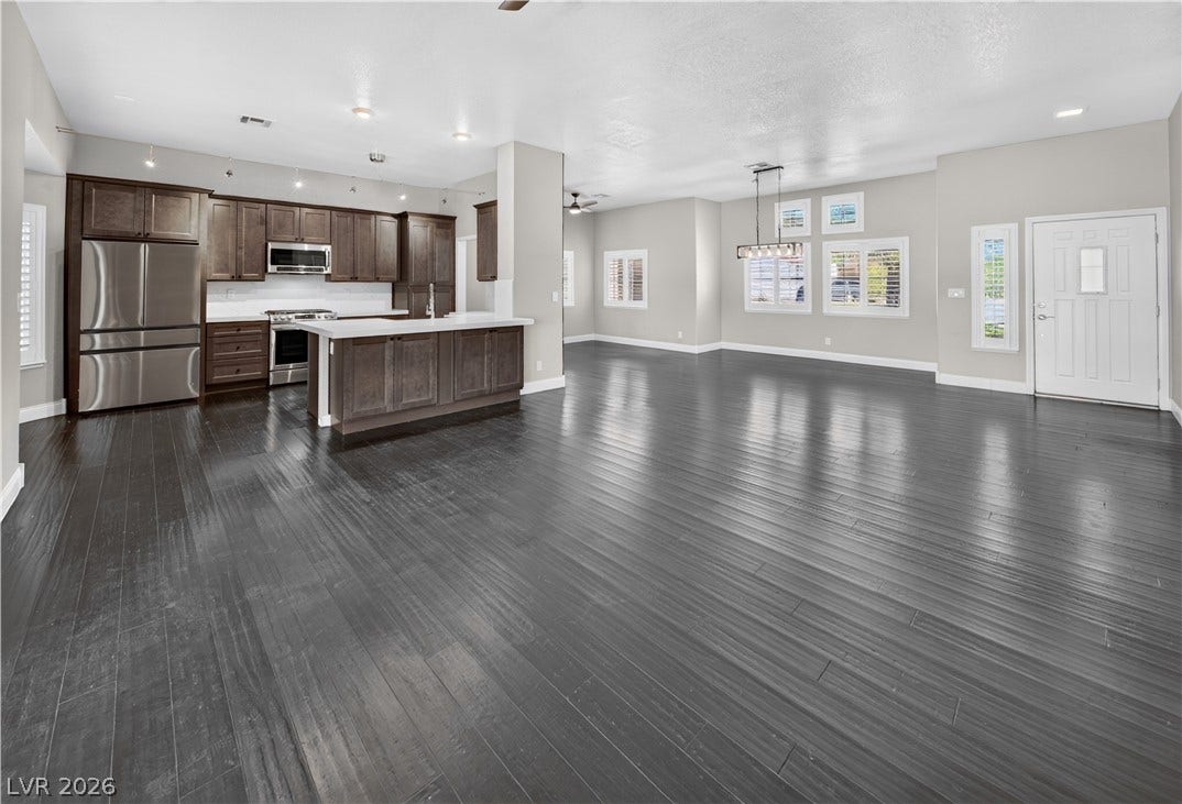 1740 Bluffs Drive, Henderson, NV 89014 Deeply toned hardwood floors anchor this expansive, open-concept space featuring a modern kitchen setup.