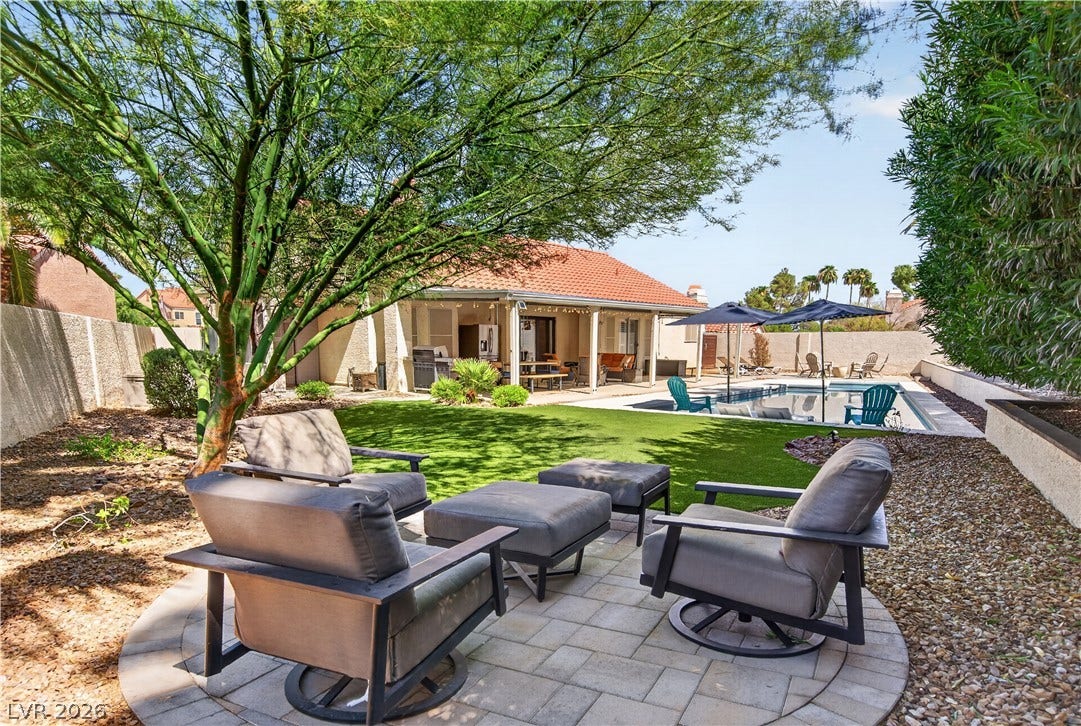 1740 Bluffs Drive, Henderson, NV 89014 An inviting stone paver patio overlooks a manicured green lawn and a sparkling backyard pool.