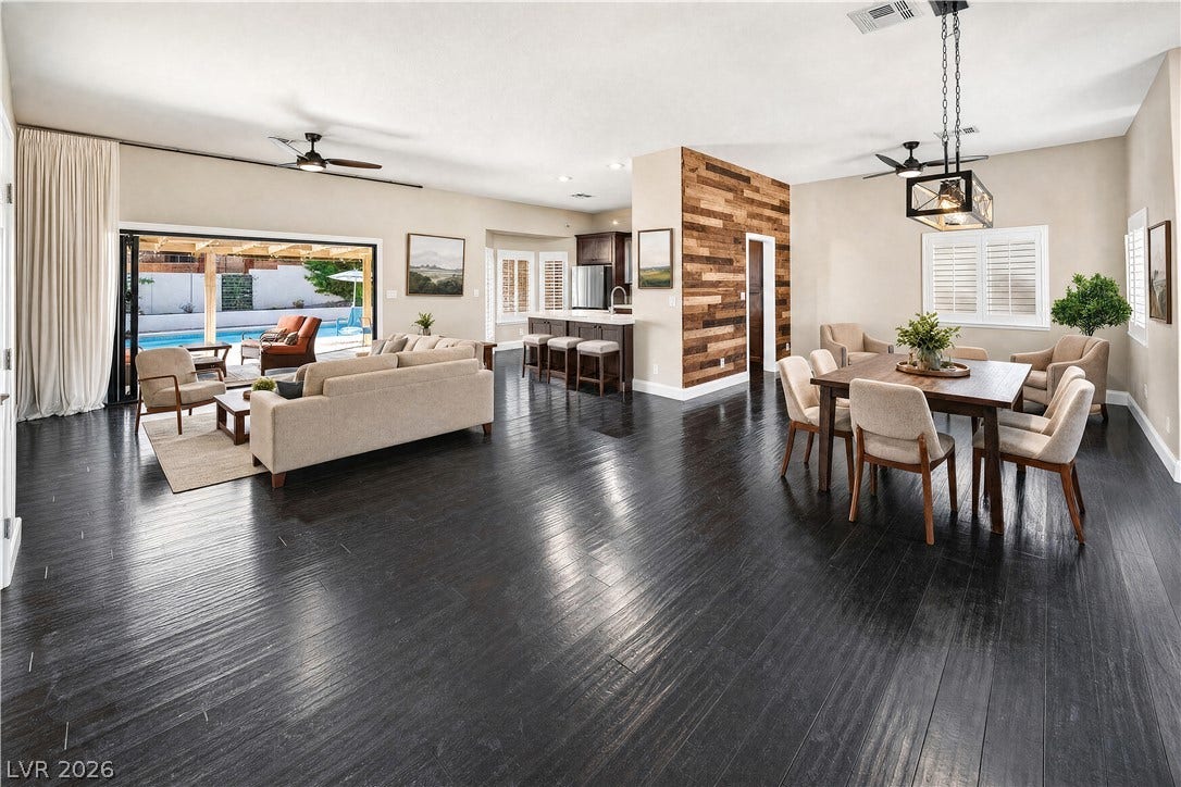 1740 Bluffs Drive, Henderson, NV 89014 Dark wood floors ground an open layout featuring a wood-plank accent wall and sliding glass doors.