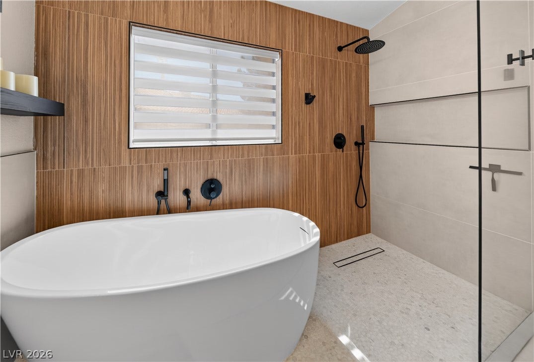 1740 Bluffs Drive, Henderson, NV 89014 Rich wood-look wall tiling pairs beautifully with sleek stone flooring in this modern bathroom.