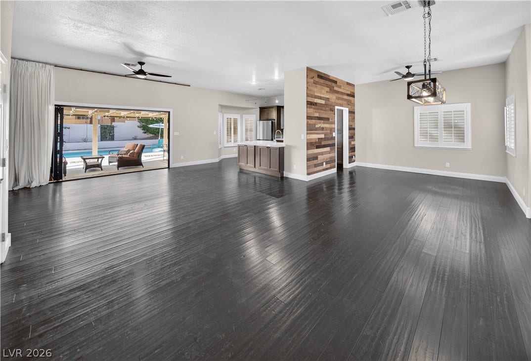 1740 Bluffs Drive, Henderson, NV 89014 Rich dark wood flooring anchors this open living space leading directly to the backyard pool.