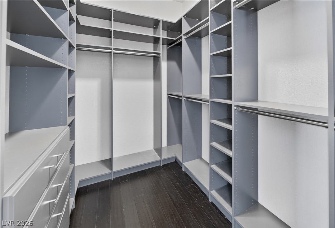 1740 Bluffs Drive, Henderson, NV 89014 Ample custom shelving and dark wood flooring define this spacious walk-in closet.