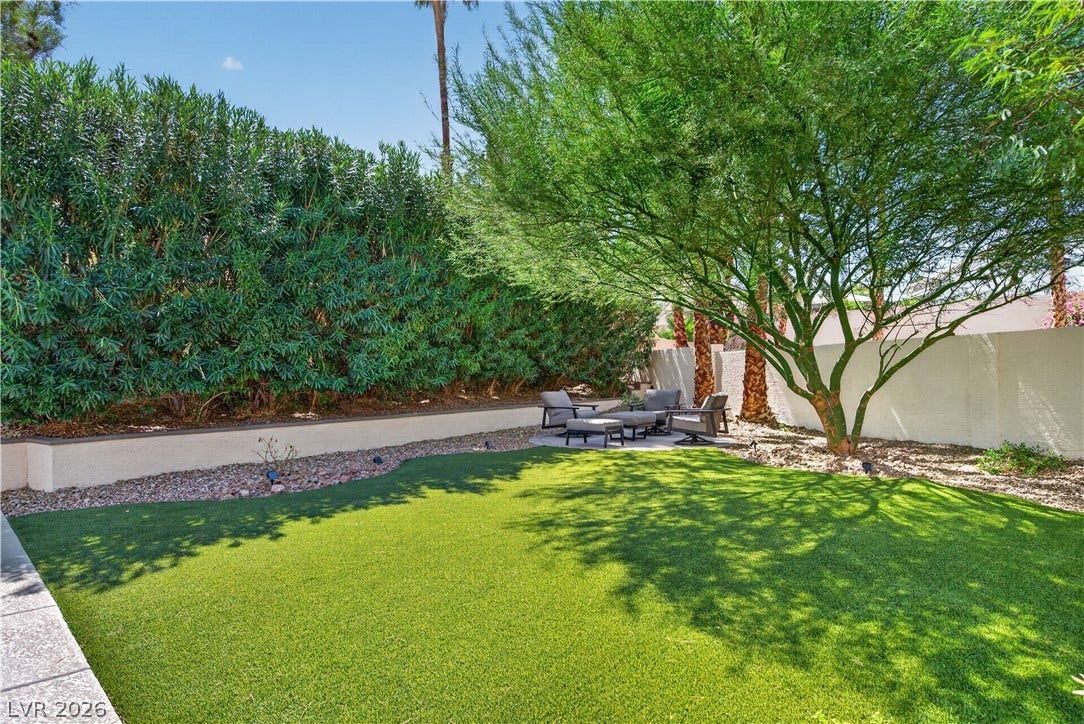 1740 Bluffs Drive, Henderson, NV 89014 Mature trees and neat privacy hedges frame a low-maintenance artificial lawn.
