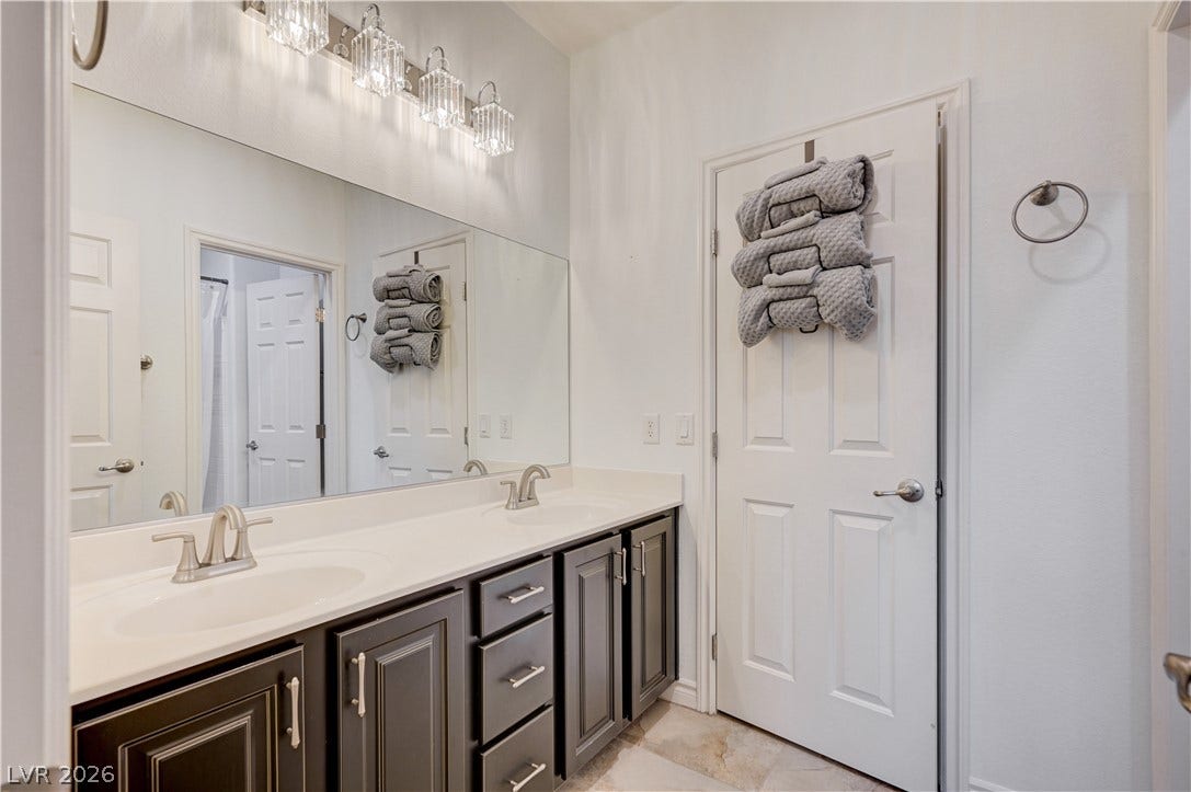 4120 Hawks Glide Avenue, North Las Vegas, NV 89084 A spacious double vanity with dark cabinetry and modern light fixtures updates this bathroom.