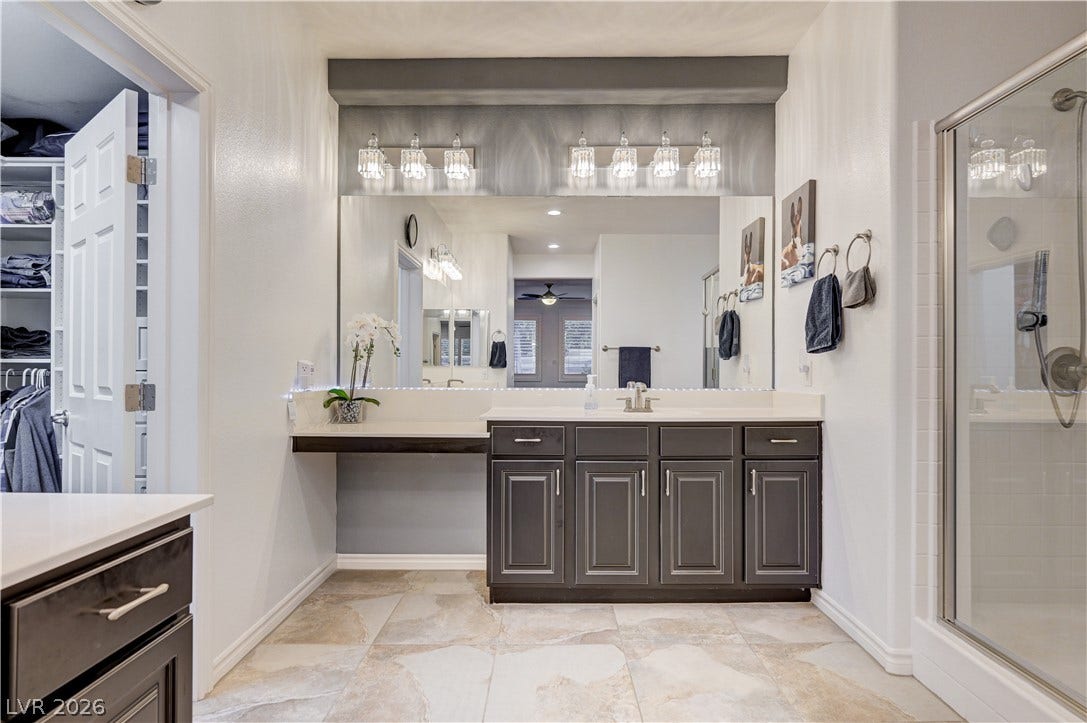 4120 Hawks Glide Avenue, North Las Vegas, NV 89084 Stone counters and custom cabinetry elevate this modern primary bath with tile flooring.