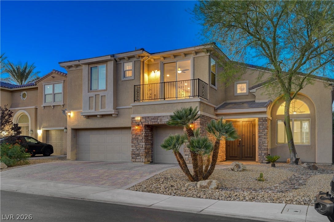 4120 Hawks Glide Avenue, North Las Vegas, NV 89084 Warm exterior lights illuminate the stone and stucco facade of this two-story desert home.
