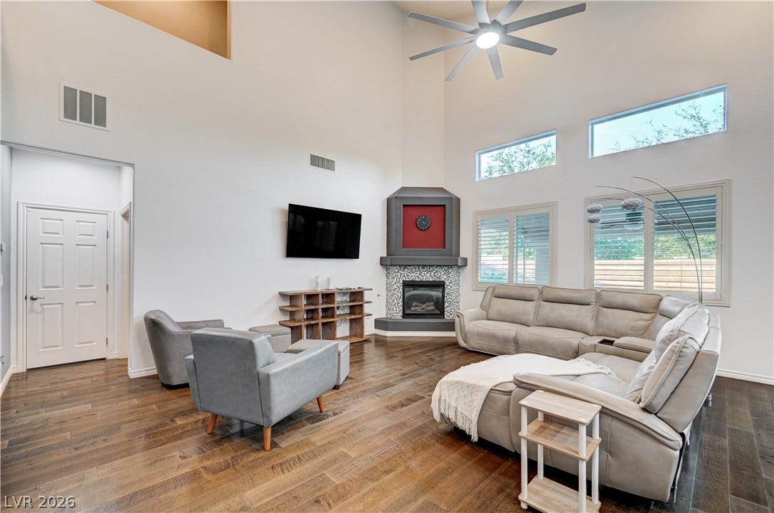 4120 Hawks Glide Avenue, North Las Vegas, NV 89084 High ceilings and rich hardwood flooring frame a cozy corner fireplace in this airy room.