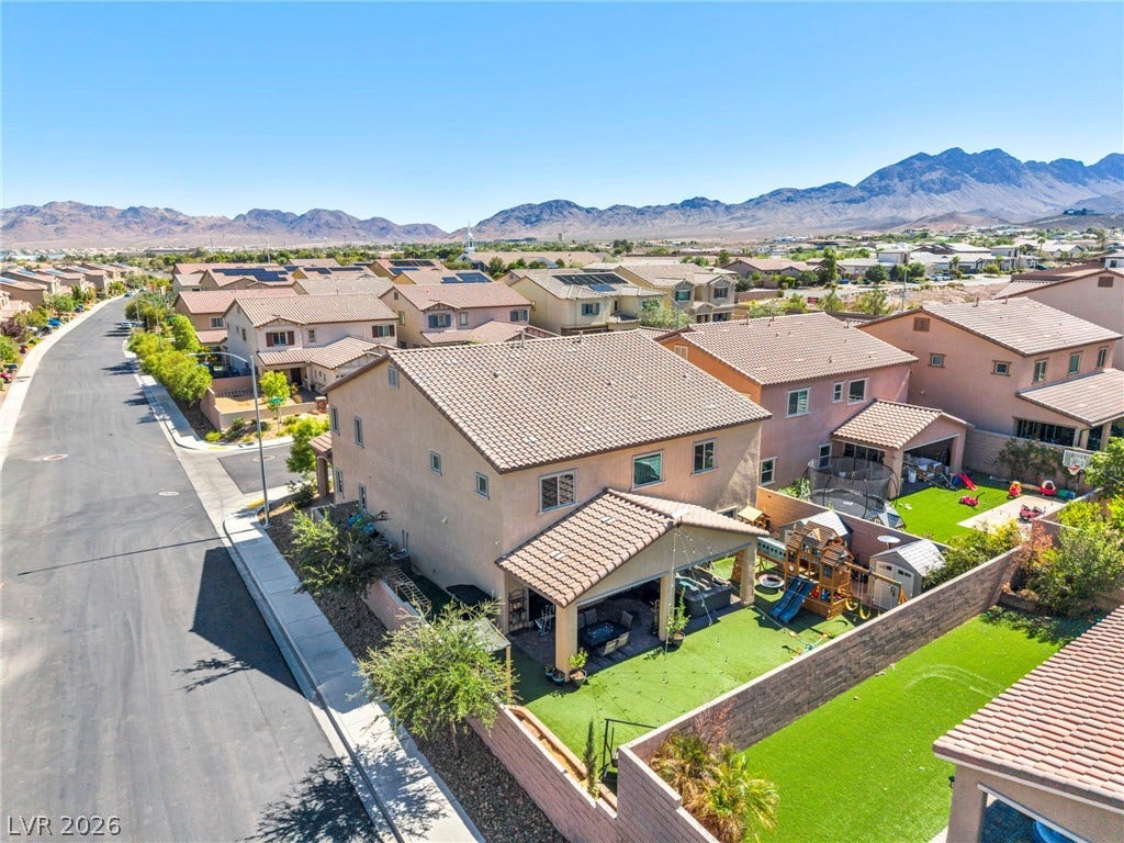 An aerial perspective showcases a suburban street nestled against a backdrop of desert mountains.