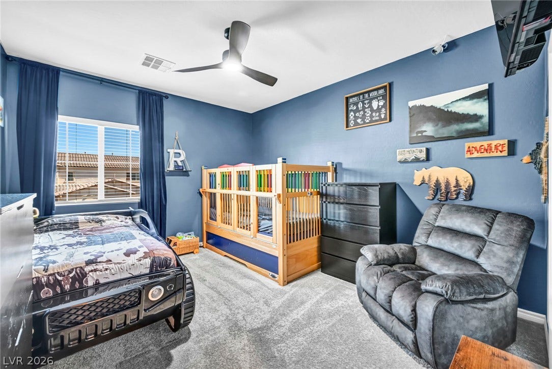 Plush carpeting and a large window create a comfortable, inviting secondary bedroom.