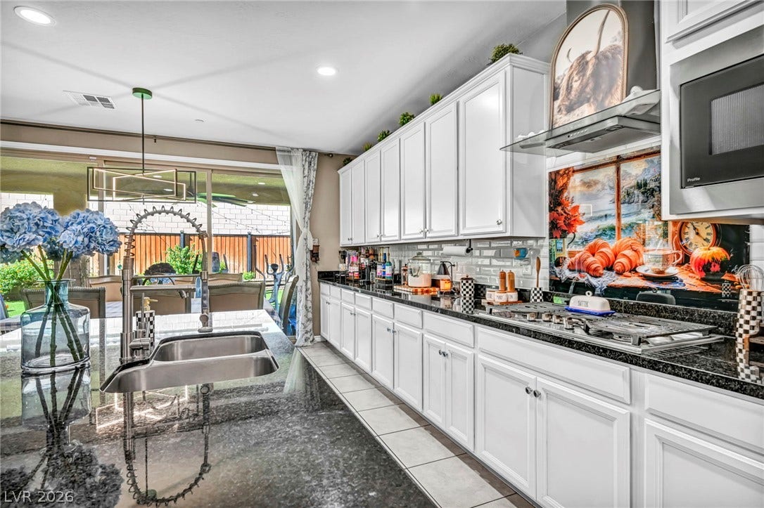 Polished stone countertops pair with abundant cabinetry in this spacious cooking space.