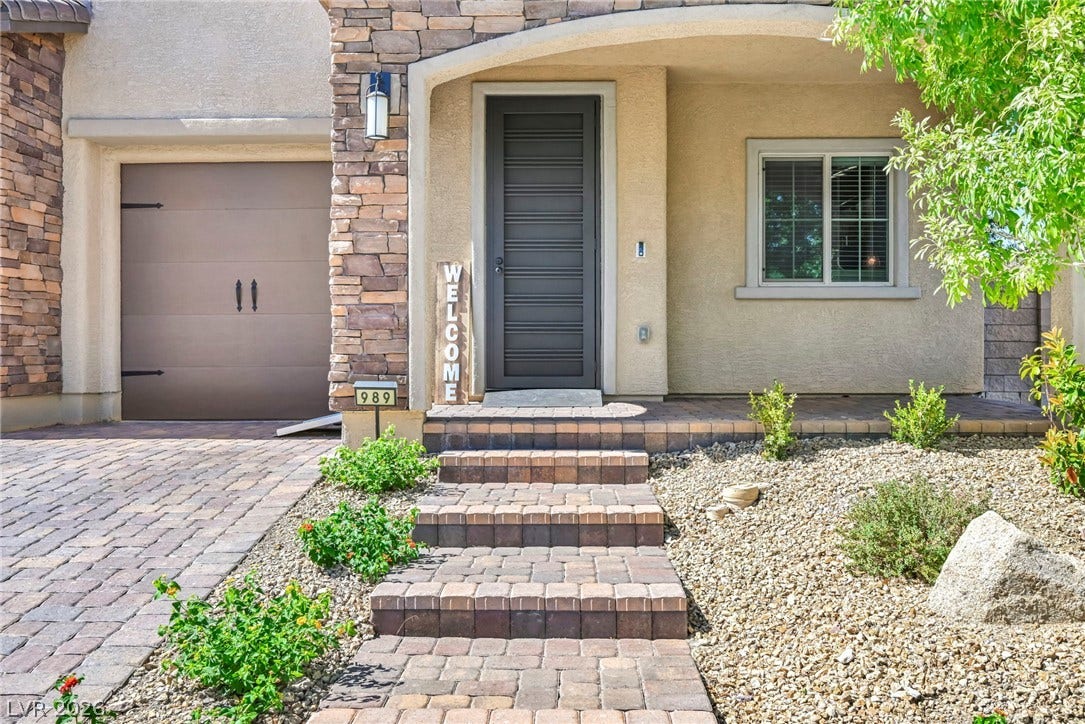 Stone accents and a paved walkway create an inviting entrance under a covered porch.