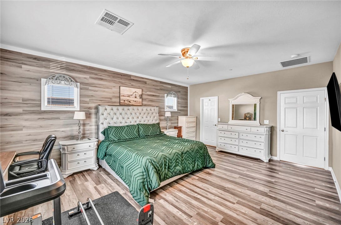 Smooth wood-look flooring and a textured accent wall define this comfortable main-level bedroom.