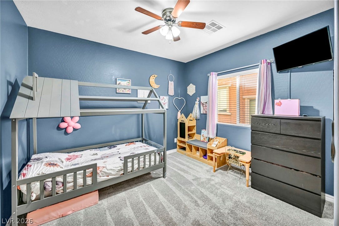 Plush carpeting and a large window create a comfortable, inviting secondary bedroom.